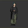 Man With Green Hair Wearing Black Coat And Green Pants Holding Camera Against Gray Background