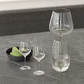 Elegant Modern Decorative Ornament Set With Glassware Black Bowl Green Fruits On Gray Countertop