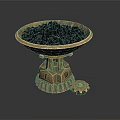 Golden Decorative Bowl With Intricate Base Holding Black Granules And Small Gear
