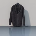 Dark Knitted Cardigan Hanging On Hanger Against Gray Wall With Smooth Floor Reflection