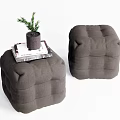 Two Dark Gray Ottoman Poufs With Magazine And Small Potted Plant On Top