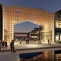 Contemporary Building Facade Featuring Wooden Arch Design Illuminated Evening Commercial Space With Pedestrians