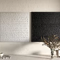 White And Black Square Textured Artworks With Raised Letter Patterns And Potted Plant