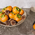 Fresh Persimmons in Brown Plate with Pine Cones Bowls and Clear Cups on Gray Tabletop