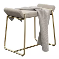 Modern Upholstered Stool With Light Gray Fabric Gold Metal Legs And Gray Blanket Draped