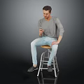 Man In Gray Shirt And Light Blue Jeans Sitting On Bar Stool Holding Smartphone