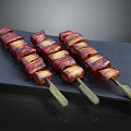 Three Roasted Pork Belly Skewers On Black Slate Plate With Glossy Surface