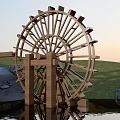 Garden Ornament With Wooden Waterwheel Grass Water Surface And Sunset Light