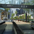 Modern Open Station with Glass Roof Escalators Palm Trees and Pedestrians Near Tall Buildings