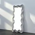 Wavy Frame Mirror With Green And Black Stripes Against White Wall And Gray Floor