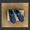 Blue Running Shoes With Multi Colored Laces And Supportive Sole On Brand Box