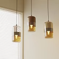 Three Modern Pendant Lights With Transparent And Brown Shades Near White Window Blinds