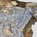 Natural Wood And Stone Landscape With Layered Rock Texture And Stream Pebbles
