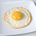 Fried Egg With Runny Yolk And Golden Edges On White Square Plate