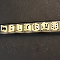 Wrought Iron Welcome Sign With Illuminated Square Block Letters On Concrete Wall