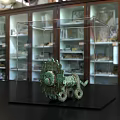 Ancient Bronze Sculpture Displayed in Clear Acrylic Case with Museum Cabinets Background