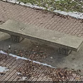 Outdoor Concrete Bench On Brick Pavement With Fallen Leaves And Snow Patches