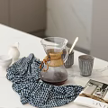 Elegant Tableware Set With Glass Coffee Pot Bamboo Accents And Checkered Cloth On Marble Countertop