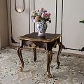 Elegant Dark Wood Side Table With Golden Carved Legs And Floral Vase On Patterned Rug