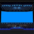 Elegant Stage Setup With Large Blue Screen And Bright Lighting Effects