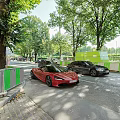Red Sports Car Parked On Street With Green Fence And Trees