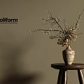 Poliform Textured Ceramic Vase with White Blossom Branches on Wooden Stool Against Beige Wall