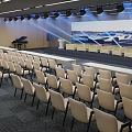 Conference Room With Neatly Arranged Chairs Large Projection Screen Stage Area Piano And Lighting Equipment