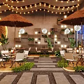 Outdoor Restaurant Design With Straw Umbrellas String Lights Stone Walls And Green Plants