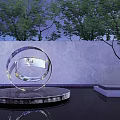 Transparent Spiral Sphere Sculpture On Circular Base With Trees And Gray Wall Reflection