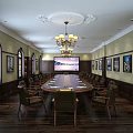 Elegant Conference Room With Chandelier Long Wooden Table Green Chairs Wall Paintings Arched Windows