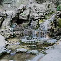 Tranquil Garden Landscape Featuring Rock Formations Small Waterfall Flowing Stream And Green Plants
