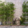 Tall Bamboo Plants Growing Against Stone Wall With Stone Sculptures And Garden Greenery