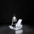 Contemporary Art Installation With Standing Figure Slanted Board And Underground Text In Dark Exhibition Space
