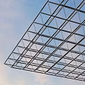 Metal Grid Frame Structure as Architectural Roof Support Against Blue Sky With Clouds