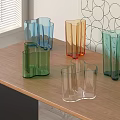 Colorful Geometric Glass Vases Arranged On Wooden Table With Window Blinds And Geometric Wall Art
