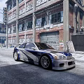 Blue and white modified car with large wheels parked in front of old factory building