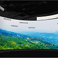 Immersive Exhibition Space With Circular Floor Blue Paths And Curved Screens Displaying Green Mountain Scenery
