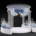 White Mesh Wedding Ceremony Arch With Blue White Flowers Yellow Lights And Round Platform