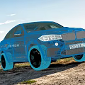 Blue BMW SUV Parked On Outdoor Dirt Road With Blue Sky White Clouds And Landscape