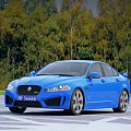 Stylish Blue Jaguar Sedan With Sleek Design And Green Trees Background