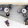 Modern Exhibition Booth Tables and Chairs with People Interacting and Display Backdrops