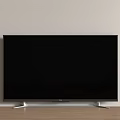 Black TV With Silver Stand On Wooden Floor Against Light Colored Wall