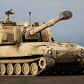 Sandy Colored Military Tank With Long Cannon And Top Mounted Equipment In Outdoor Setting