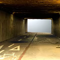 Concrete Tunnel Structure with Graffiti Covered Walls Damaged Ground Arrows and Light at End