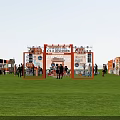 Outdoor Exhibition Event With Stage Orange Booths Seating Area And Crowd Activities