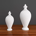 Two White Ceramic Vessels with Spiral Patterns on Wooden Tabletop Against Gray Background