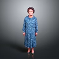 A Woman In Blue Floral Dress Standing Against Gray Background Smiling With High Heels