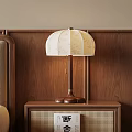 Bedside Table With Rattan Detail And Wooden Table Lamp With Beige Lampshade On Wooden Wall