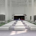 Spacious Indoor Event Venue With Neatly Arranged White Benches Decorated Stage And Large Screen