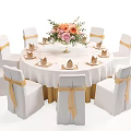 Banquet Hall Setup With Round White Tablecloth Flower Bouquet And Gold Ribbon Chairs